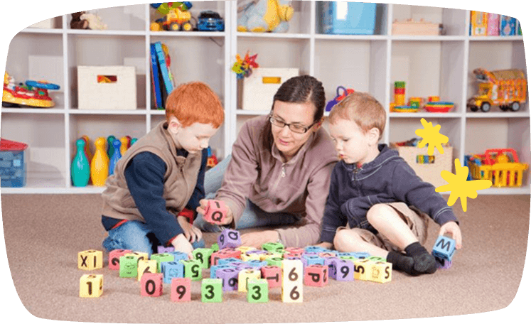 oppas speelt op de grond met twee oppaskinderen